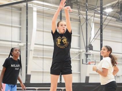 A player holds a shooting follow-through while two teammates watch.